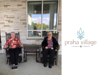 Residents at Praha Village sit outside on gliders.