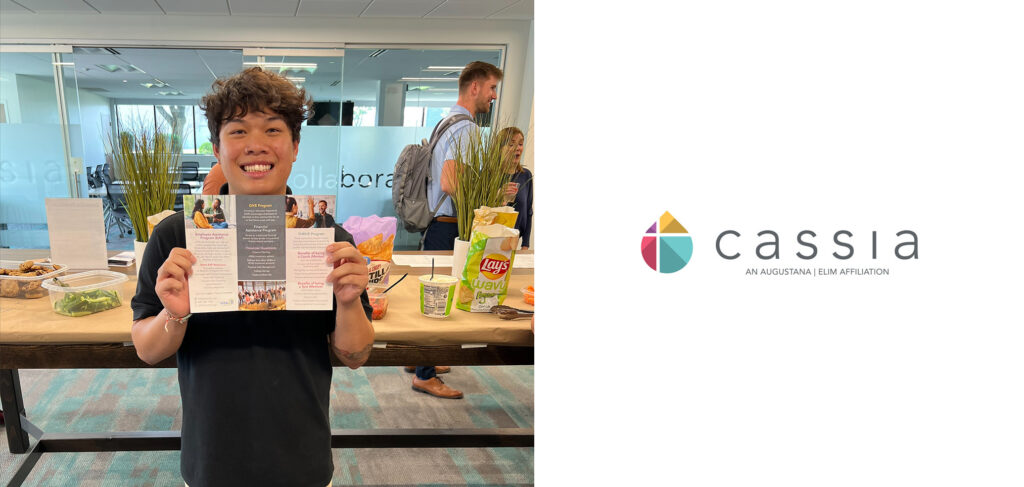 Devon, the Diversity and Inclusion Intern at Cassia, smiles while holding a brochure during his farewell gathering at the Cassia Home Office, surrounded by snacks and drinks. The staff celebrated Devon's impactful contributions to promoting inclusivity within the community as he prepares to head off to school.
