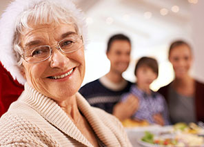 Smiling senior woman at a gathering in a private dining room, enjoying a meal with family and friends.