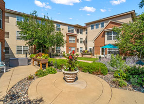 Beautiful outdoor patio and sculpture garden surrounded by greenery and seating areas in a senior living community.