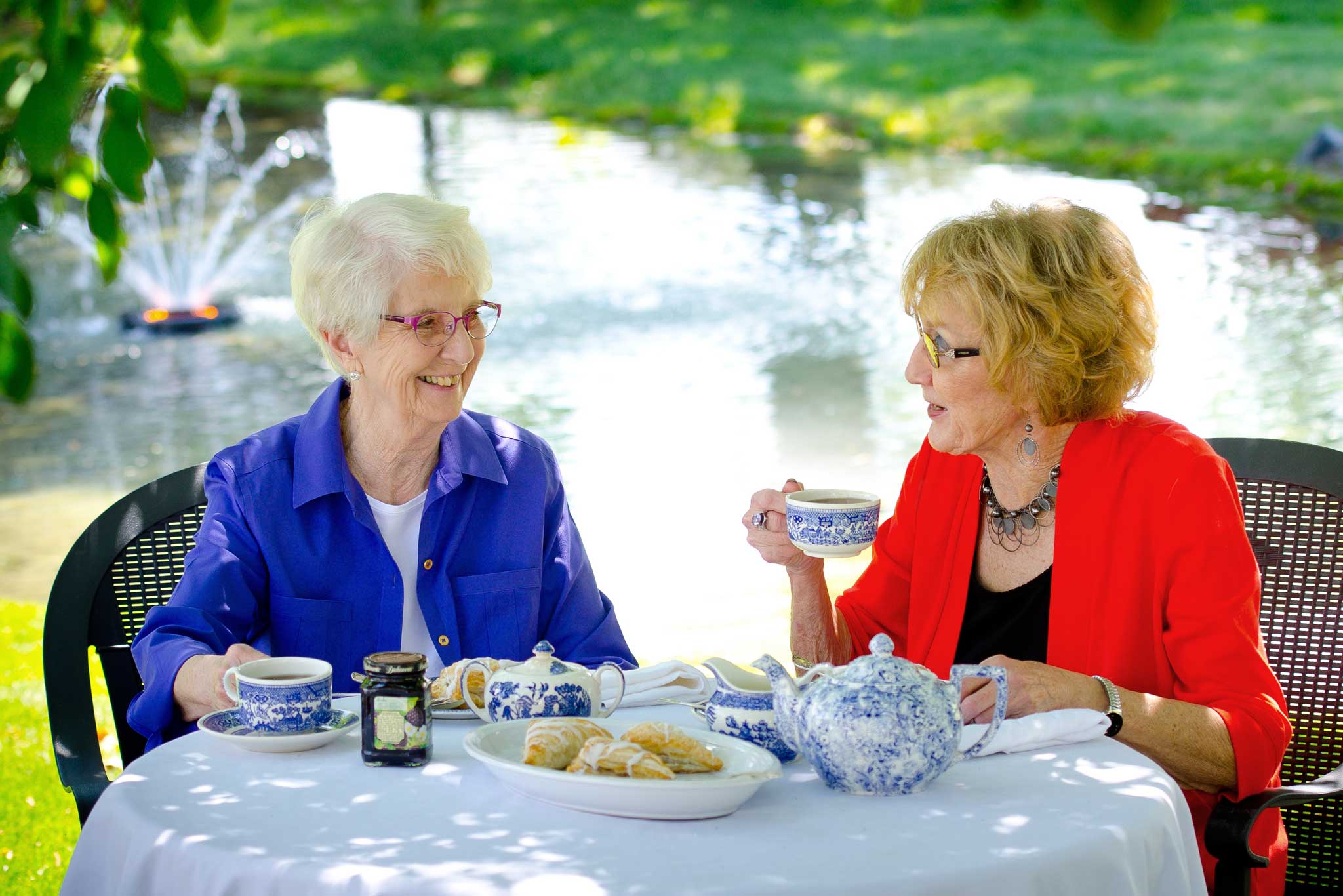 Two women enjoy tea and pastries by the pond during The Pines’ Mother’s Day tea celebration.