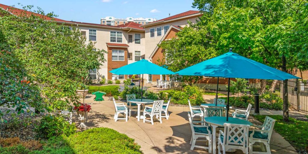 Outdoor patio at The Pines of Richfield, set with tables and bright teal umbrellas—site of the upcoming Sweet Sounds summer music and happy hour events.