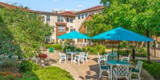 Outdoor patio at The Pines of Richfield, set with tables and bright teal umbrellas—site of the upcoming Sweet Sounds summer music and happy hour events.