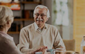 Two seniors enjoying coffee and conversation in a cozy kitchen setting, representing independent living lifestyle like The Pines of Richfield in Richfield, Minnesota