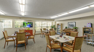 Activity room with tables, chairs, art supplies, and games arranged throughout at The Pines of Richfield in Richfield, Minnesota