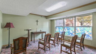Small chapel space with chairs, cross on the wall, and stained glass-style window at The Pines of Richfield in Richfield, Minnesota