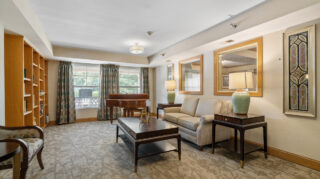 Comfortable lounge living room with sofa, chairs, coffee table, and large windows at The Pines of Richfield in Richfield, Minnesota