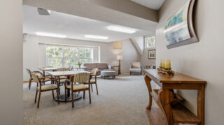 Spacious lounge area with tables, chairs, sofa seating, and large windows under a vaulted ceiling at The Pines of Richfield in Richfield, Minnesota