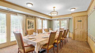 Private dining room with a long table, chairs, place settings, and large windows in a comfortable setting at The Pines of Richfield in Richfield, Minnesota
