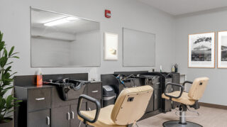 Salon space with styling chairs, wash stations, mirrors, and cabinetry at The Pines of Richfield in Richfield, Minnesota