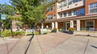 Main entrance at The Pines of Richfield featuring a covered entry, benches, and landscaped outdoor spaces.